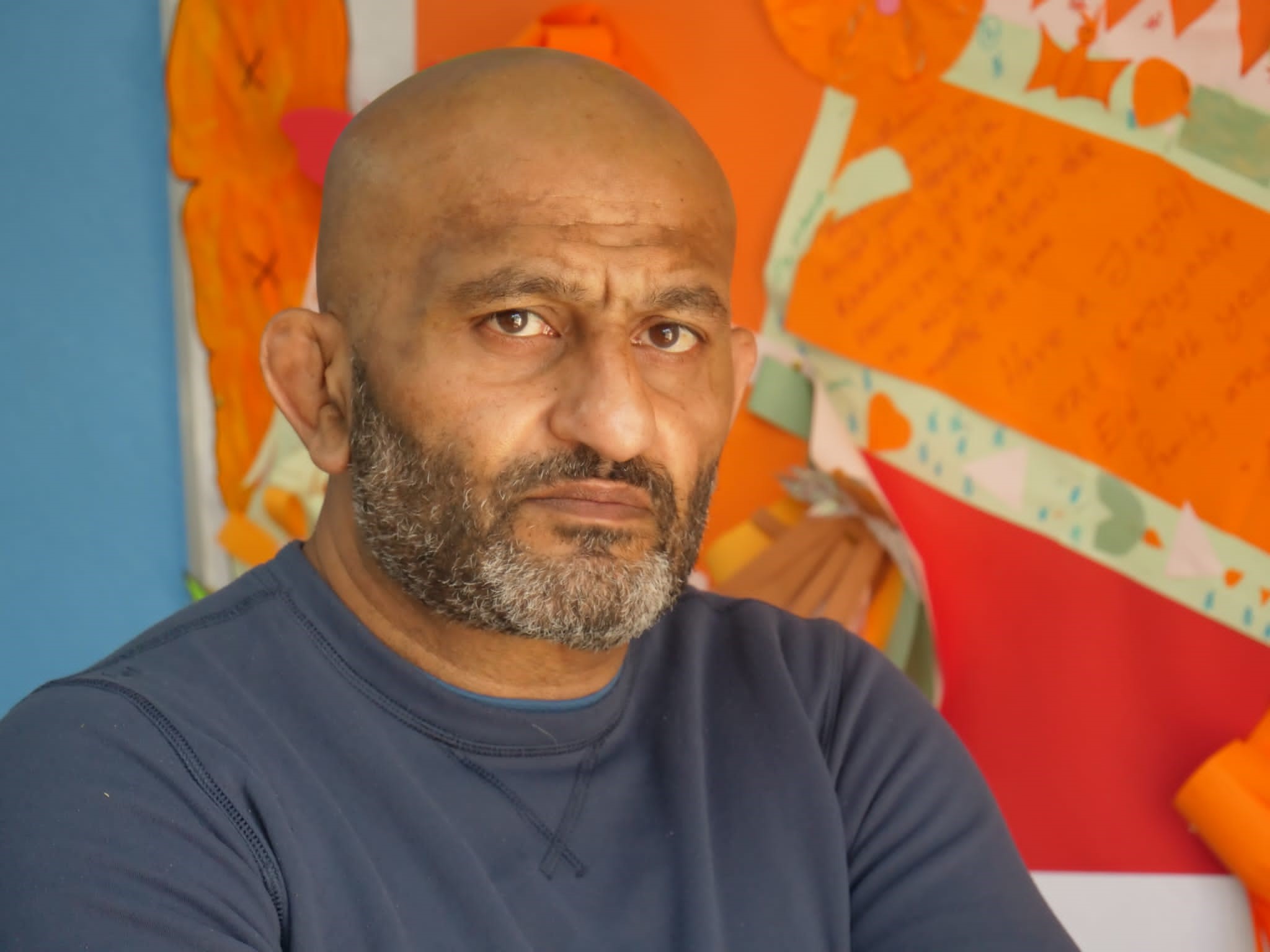 Portrait of Salman Mirza against a bright orange background