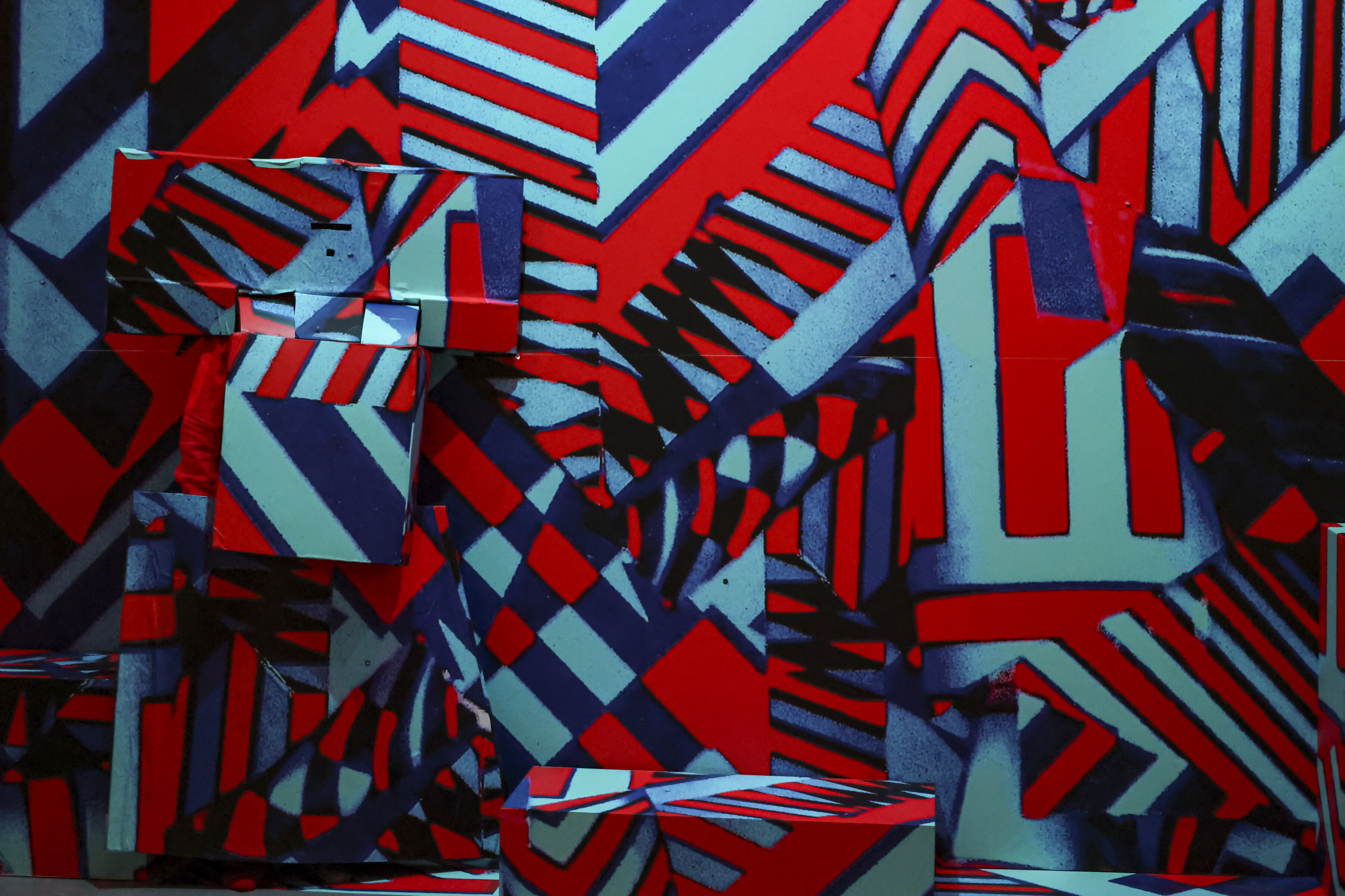 This image shows artist Aaron Williamson performing Hiding in 3D against a blue and red geometric design.