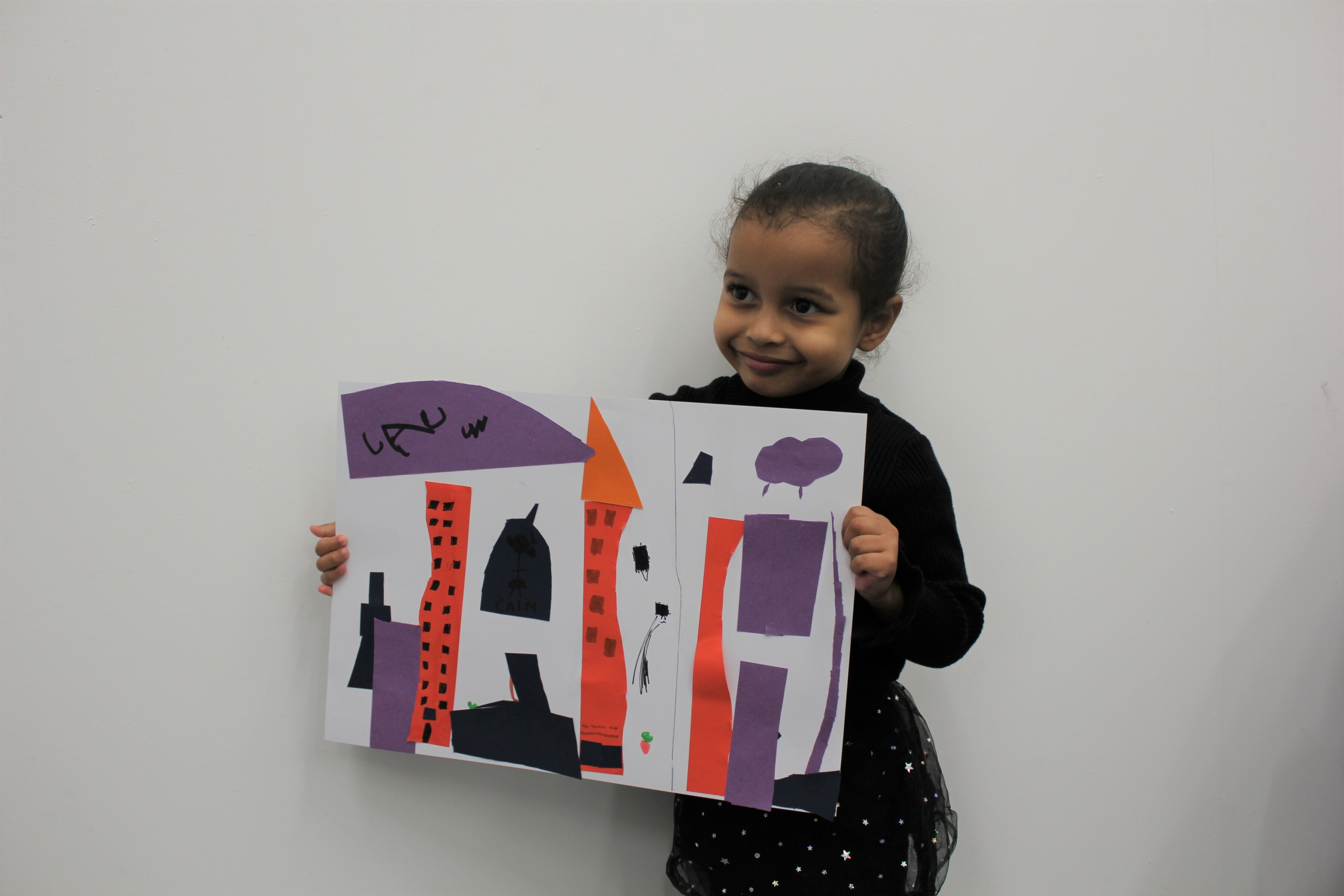 Child holding art work whilst smiling at the camera
